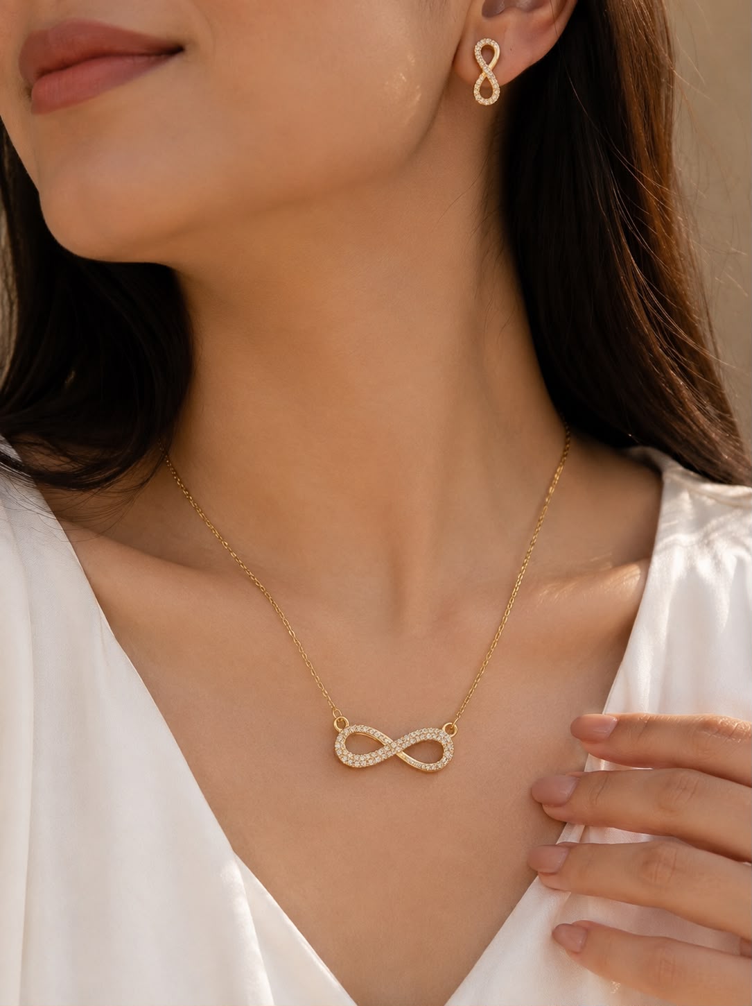 Model wearing infinity CZ necklace and earrings set in gold tone