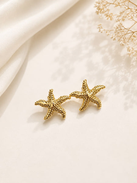 Gold textured starfish stud earrings flat lay