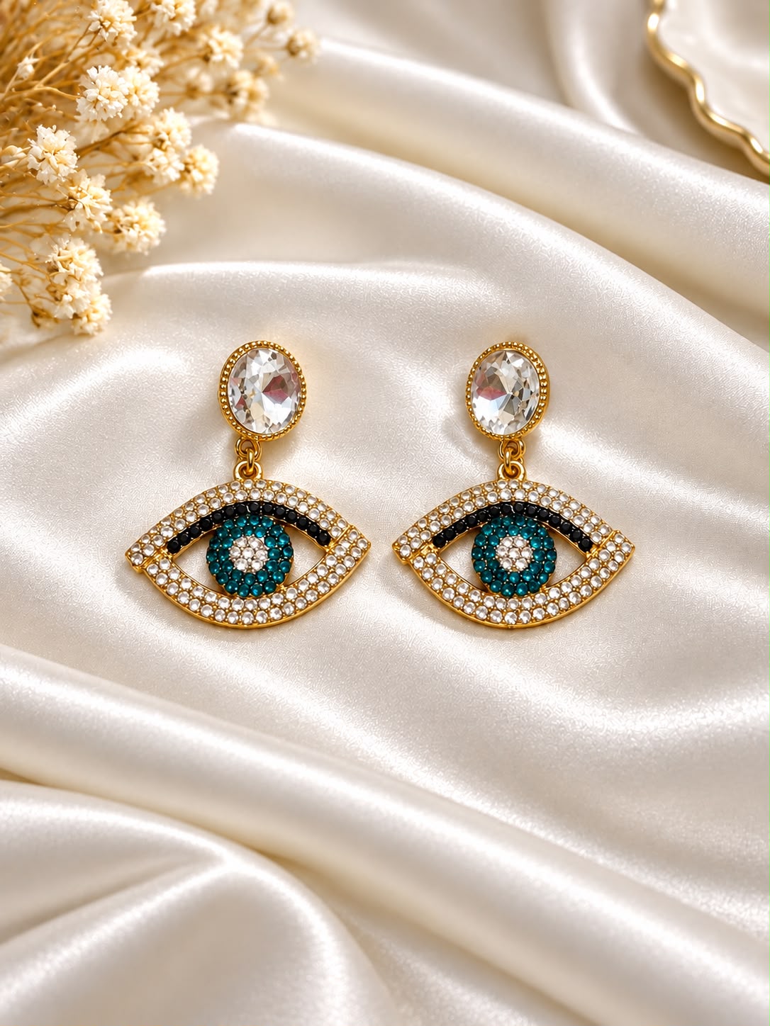 Gold-tone eye-motif earrings with teal centres and clear stones