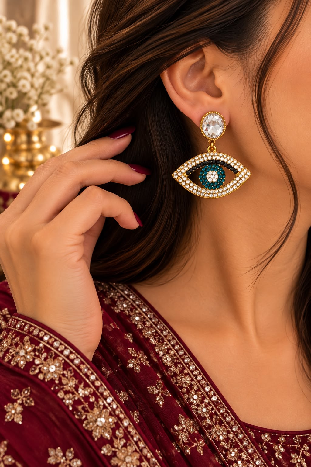 Model wearing teal eye-motif statement earrings