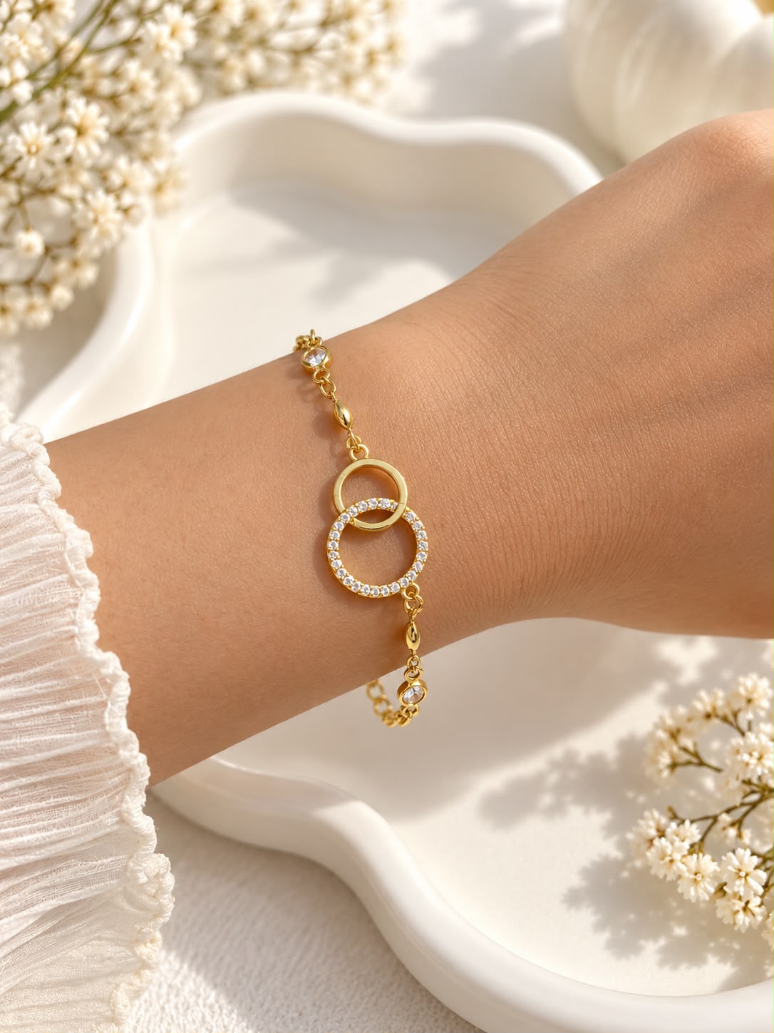 Gold-tone interlocking circle bracelet with clear stone accents worn on a wrist