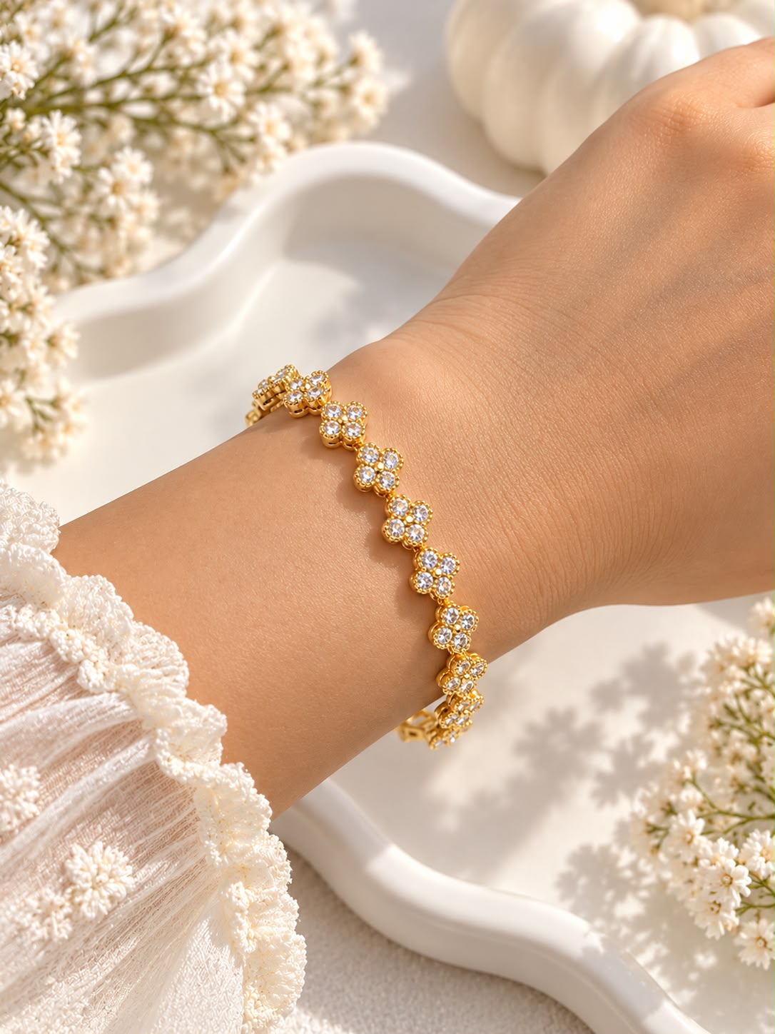 Gold-tone floral clover bracelet with clear stones worn on a wrist