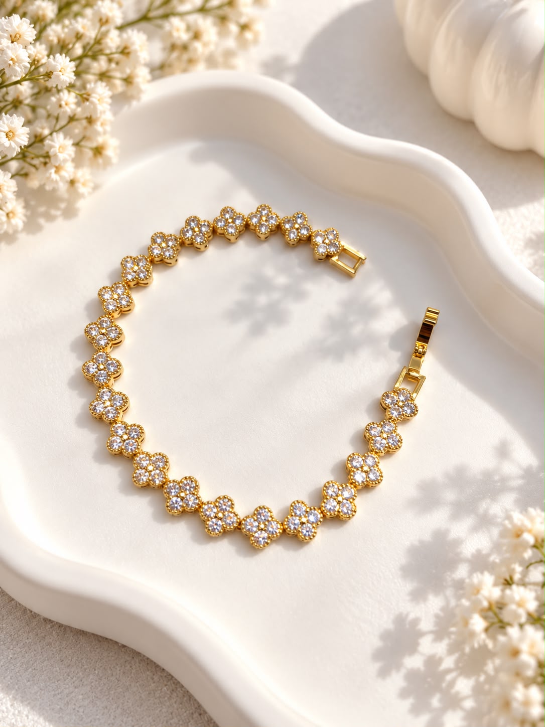 Gold-tone floral clover bracelet laid flat showing clasp and clear stone detailing