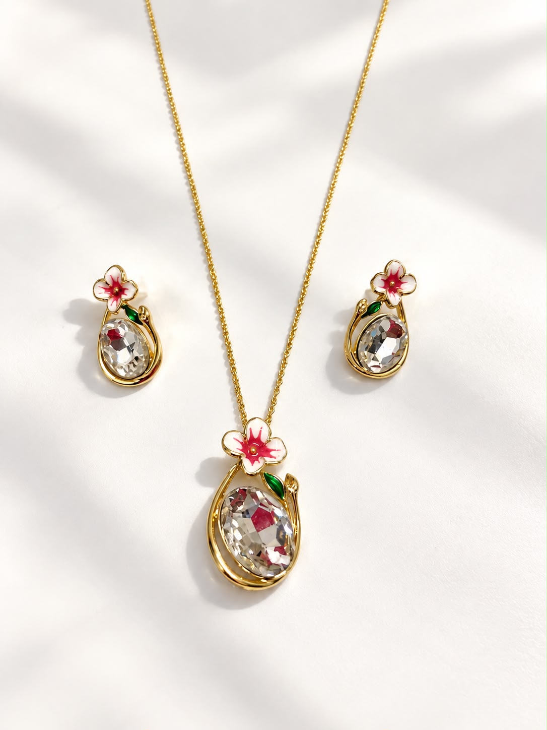 Pink blossom oval crystal pendant necklace and earrings flat lay - The Decus