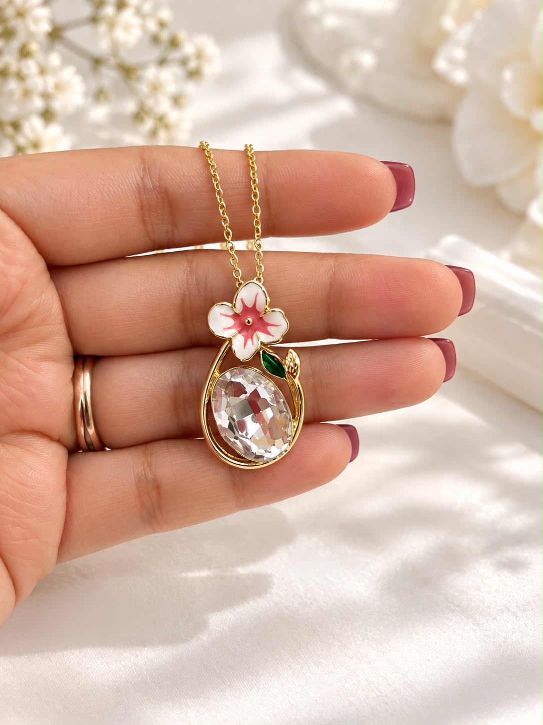 Pink blossom oval crystal pendant held in hand - The Decus