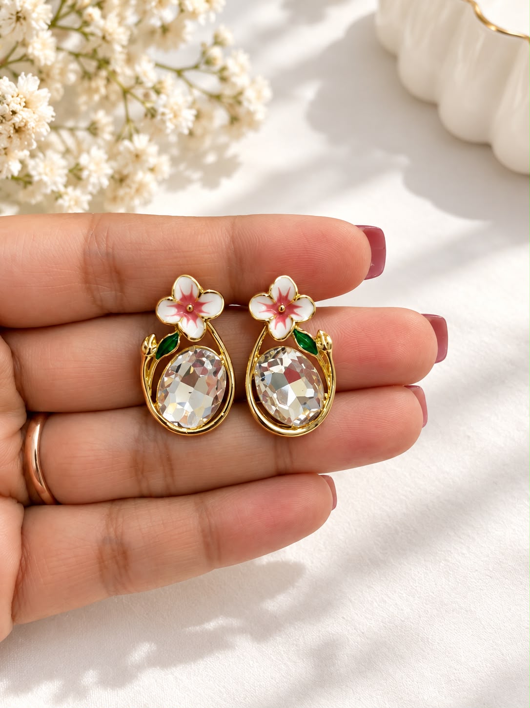 Pink blossom crystal earrings held in hand - The Decus