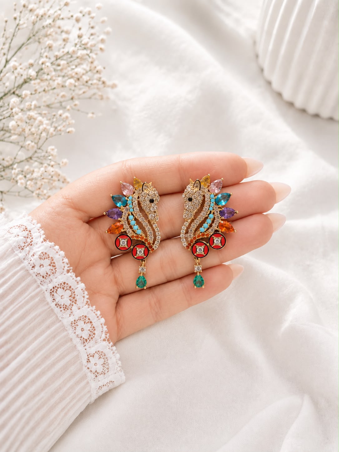 Unicorn crystal and enamel drop earrings held in hand to show scale