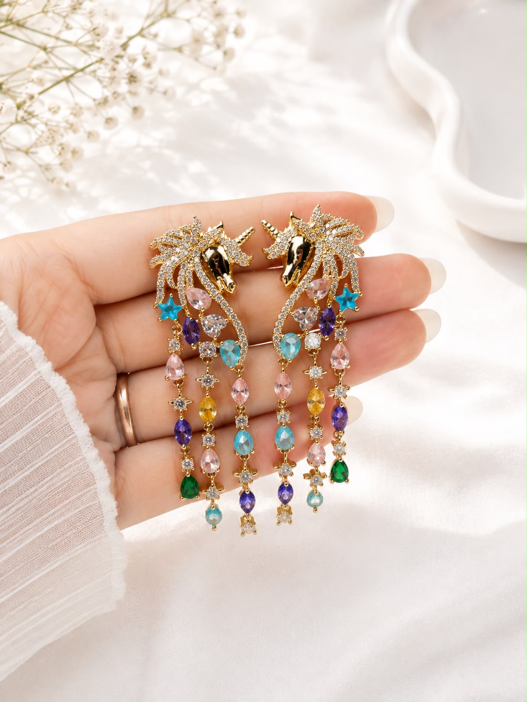 Unicorn cascade tassel earrings held in hand to show length