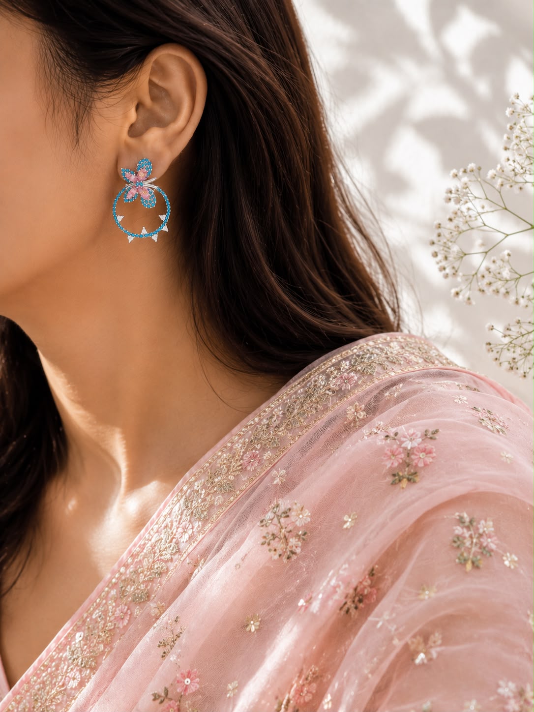 Model wearing turquoise butterfly hoop earrings with a pink organza saree